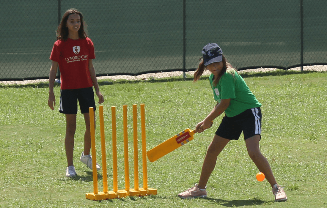 Two students playing cricket.